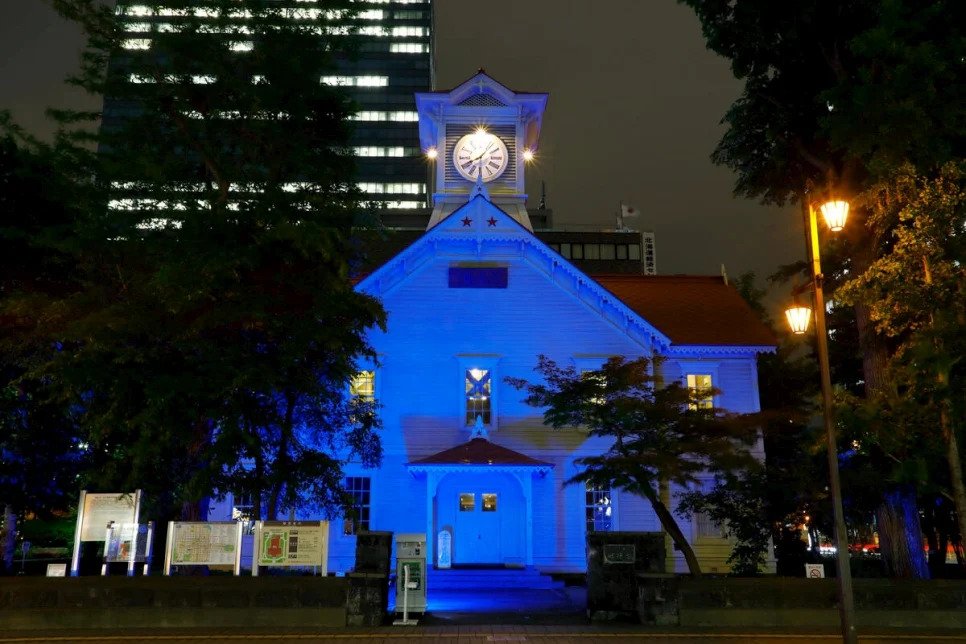 white clock tower with a blue light projected on to the front of the building