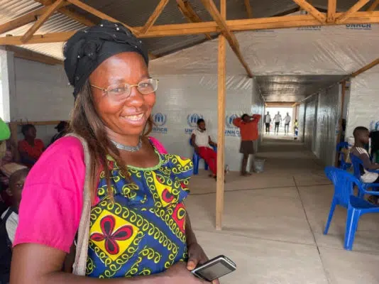 woman standing smiling to the camera inside a room with wood pillars along the ceiling