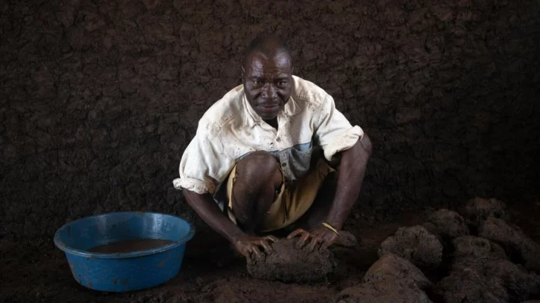 Patrício Alberto Mponda mixes water with mud that will be used to build the walls of his new home in Corrane site for displaced people. © UNHCR/Hélène Caux