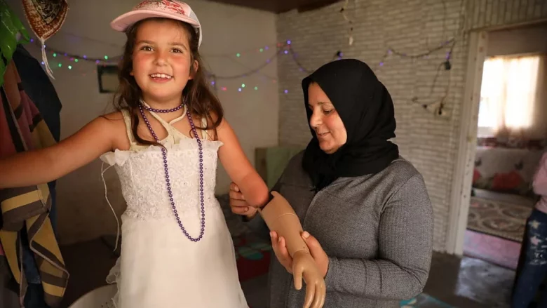 Safiyah helps Sarah to attach her prosthetic arm, which was provided by Lebanese NGO Bionic Family.  © UNHCR/Houssam Hariri