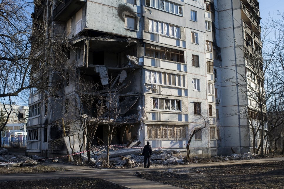 Person standing in front of a partially destroyed building.