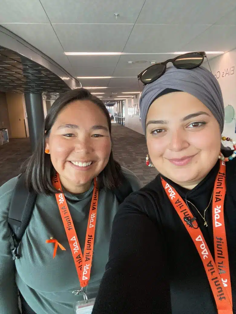 Two people stand next to each other for a selfie with an orange lanyard that says Air Inuit on it.