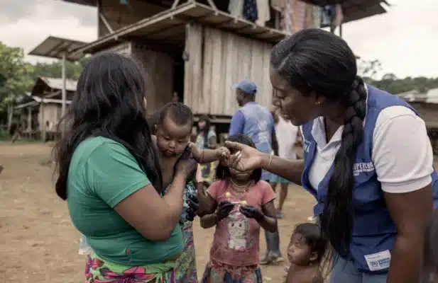 Woman is holding a child on the left while the woman on the right is holding the baby's hand.