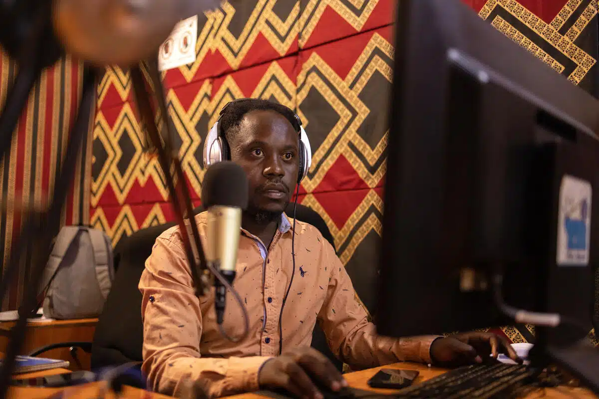A man sits at a recording booth