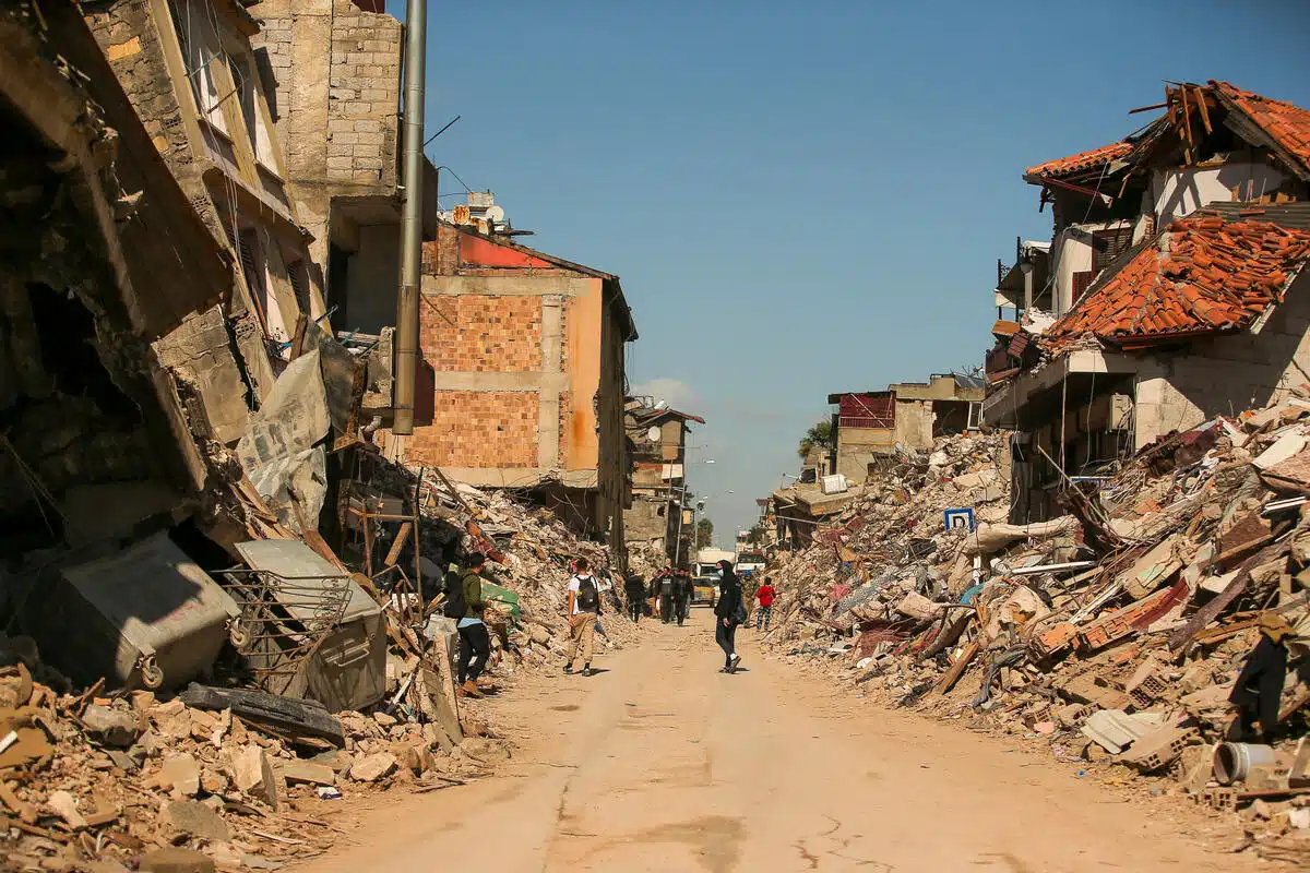 People walk on a street with rubble on either side 