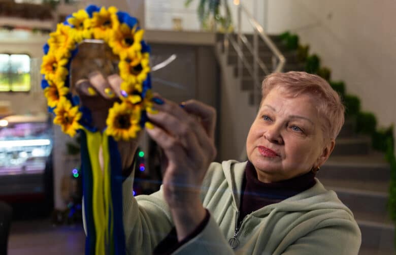A woman puts up a sunflower decoration on a window