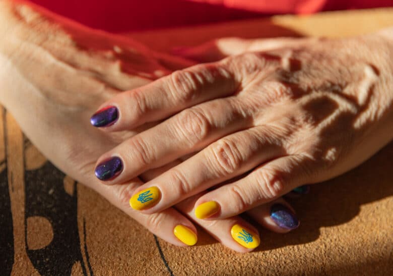 Close up of a woman's hands with ukrainian symbols and colors painted on her nails.