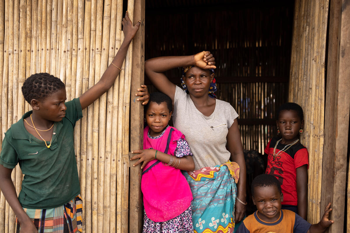 A woman and a child lean against a bamboo door
