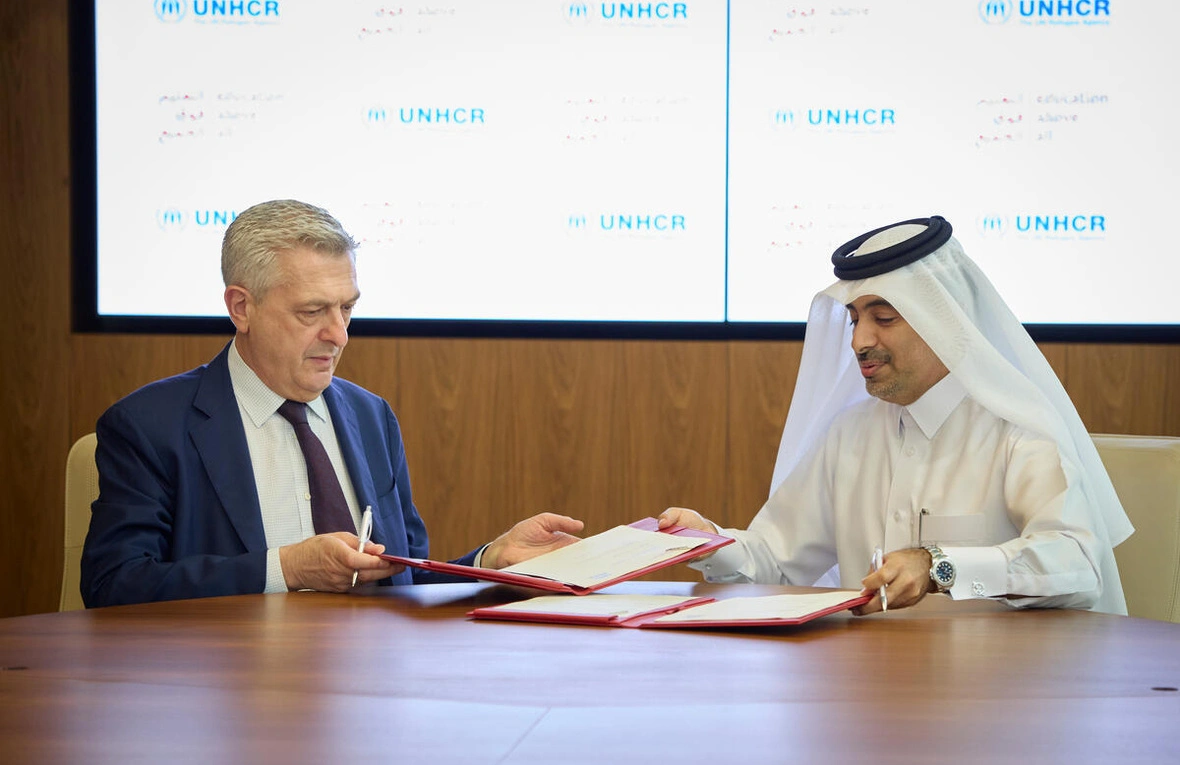 Two men sitting at a table discussing over documents.