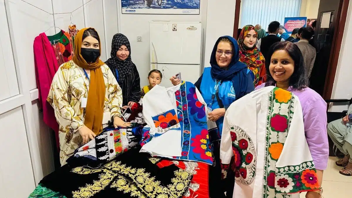 A joyful group of people are standing around a table, holding what seems to be traditional clothing.
