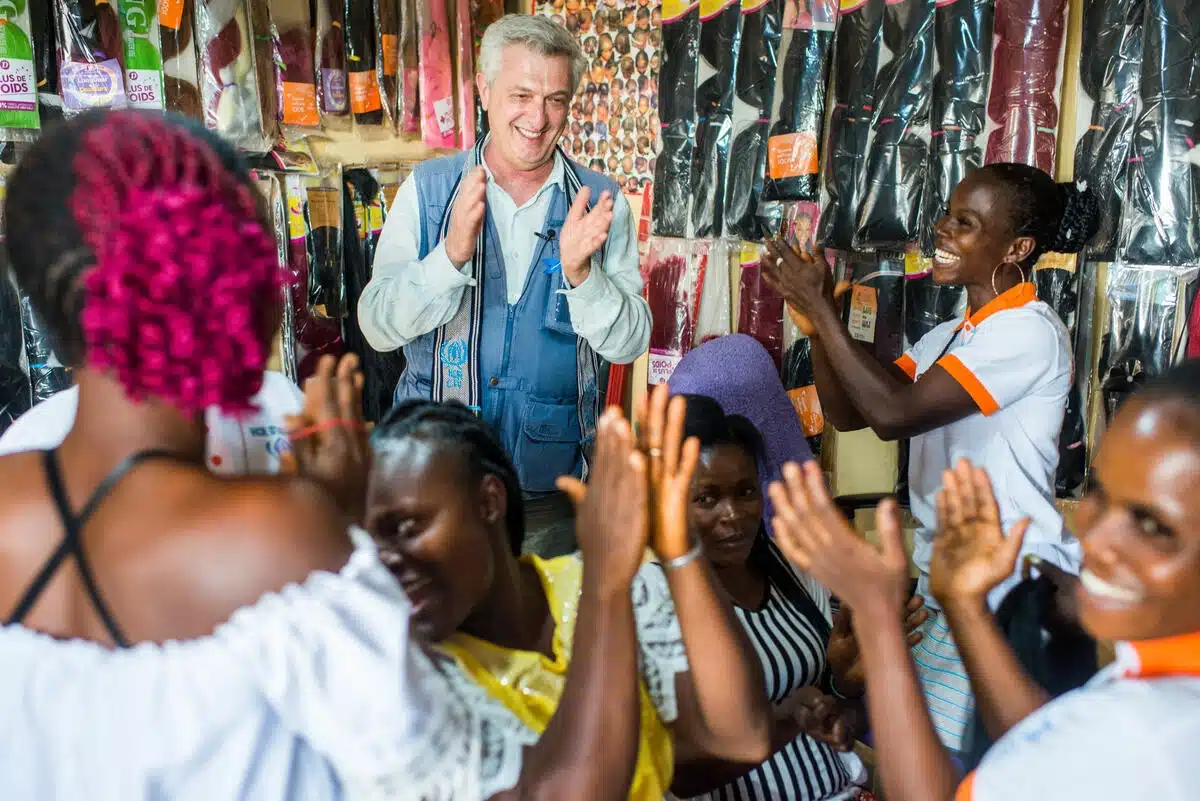UNHCR High Commissioner Filippo Grandi is in a hair salon with a group of women. They look festive and are clapping hands.