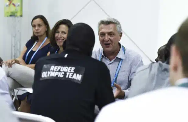 High Commissioner Filippo Grandi is talking to a person wearing a Refugee Olympic Team labelled shirt.
