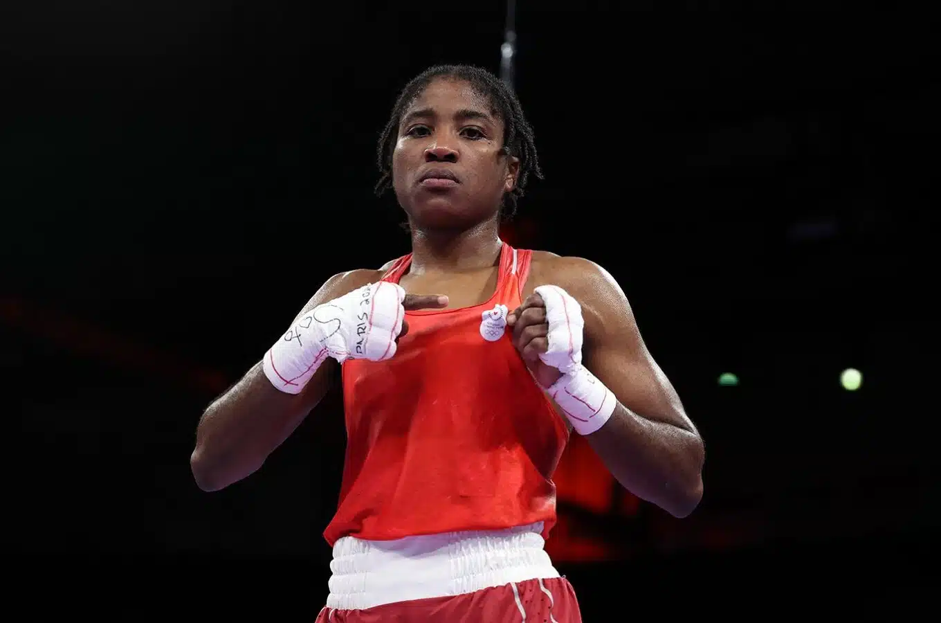 Woman in red tank top and red and white shorts with white tape around hands.