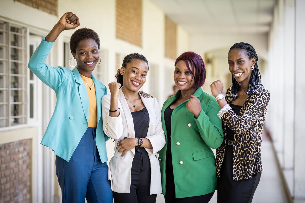 Quatre jeunes femmes noires se tiennent dans un couloir et brandissent leurs poings en souriant triomphalement à la caméra.