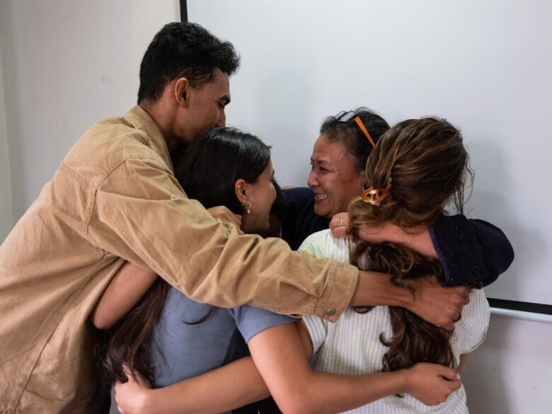 Trois femmes et un homme s'embrassent joyeusement.