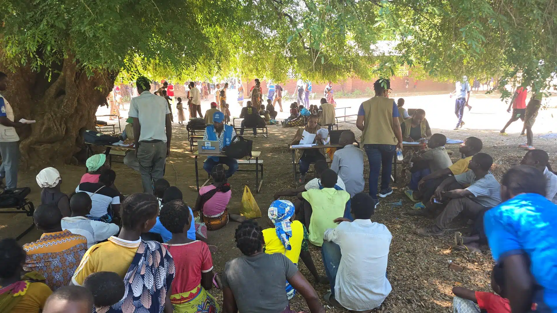 Un groupe de réfugiés mozambicains est assis à l'ombre d'un grand arbre et attend son tour pour s'enregistrer auprès du HCR dans le district de Nsanje au Malawi. 