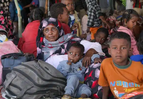 A Sudanese woman and her grandchildren sit on the ground amid mounds of luggage at a tightly packed reception centre in South Sudan.