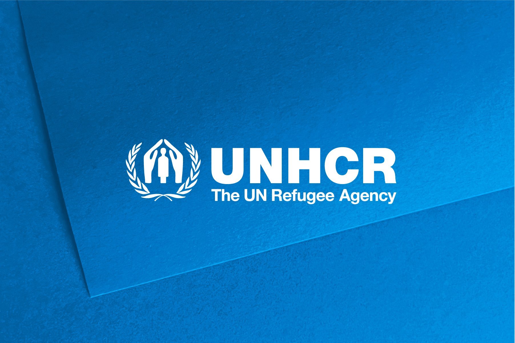 White UNHCR logo on light blue background