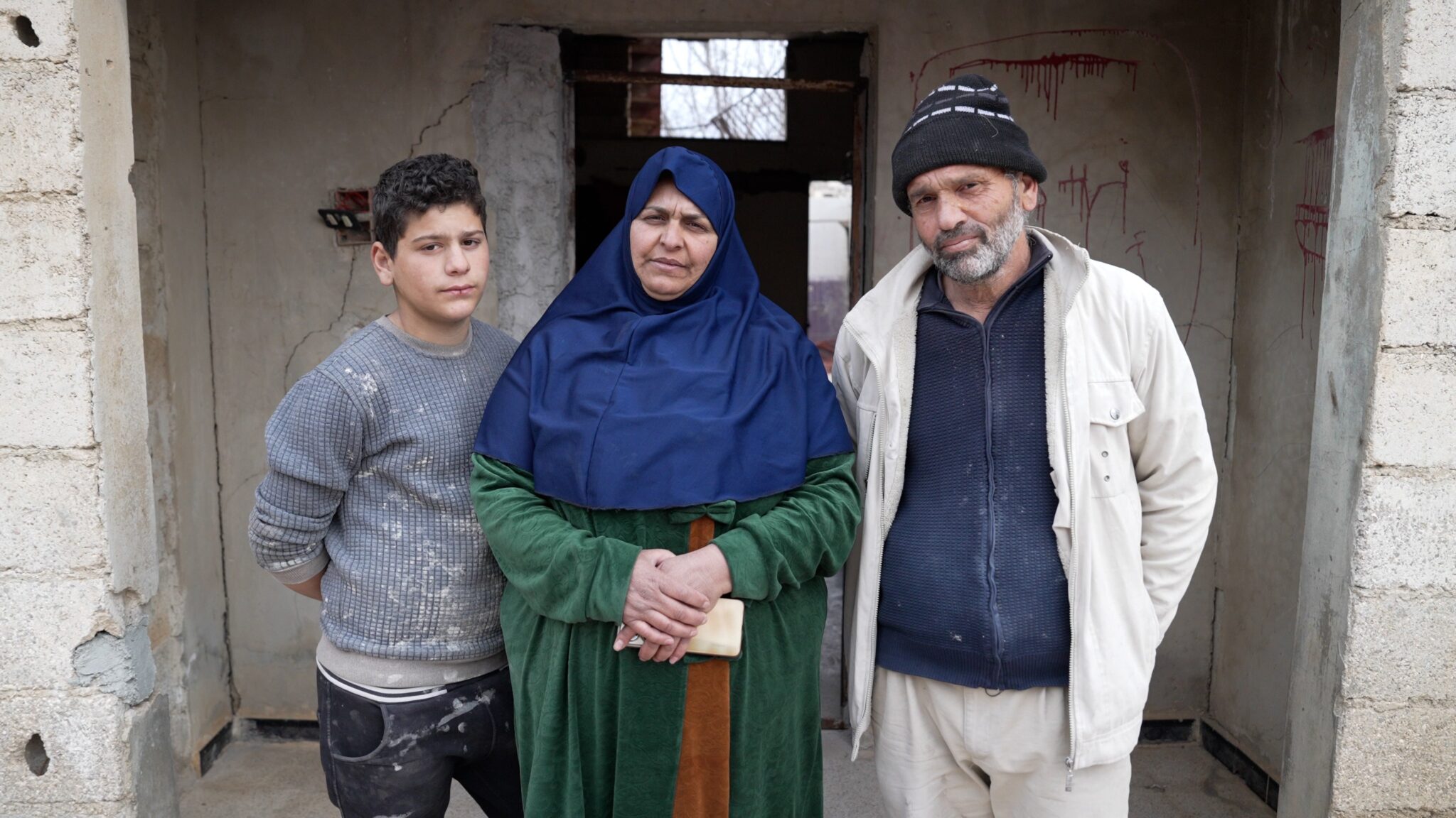 A family of three members stands outside of their newly built house