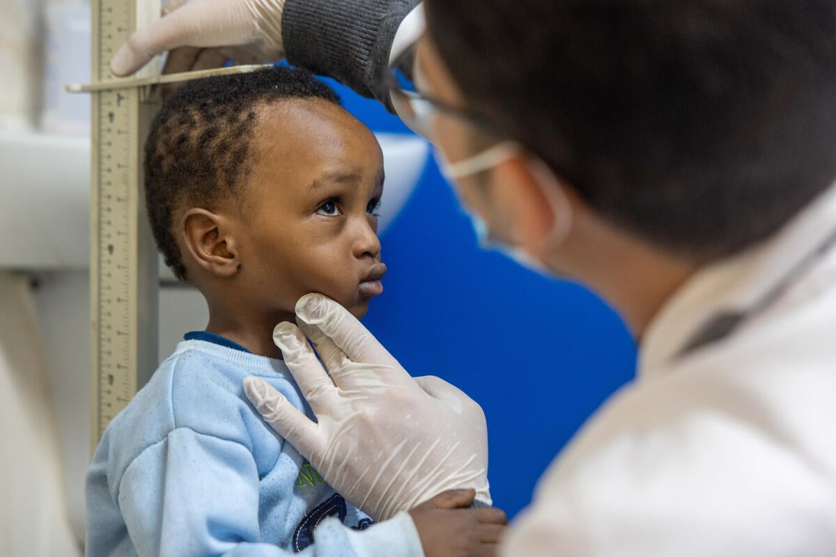 A two-year old boy is being examined and measured by a doctor.