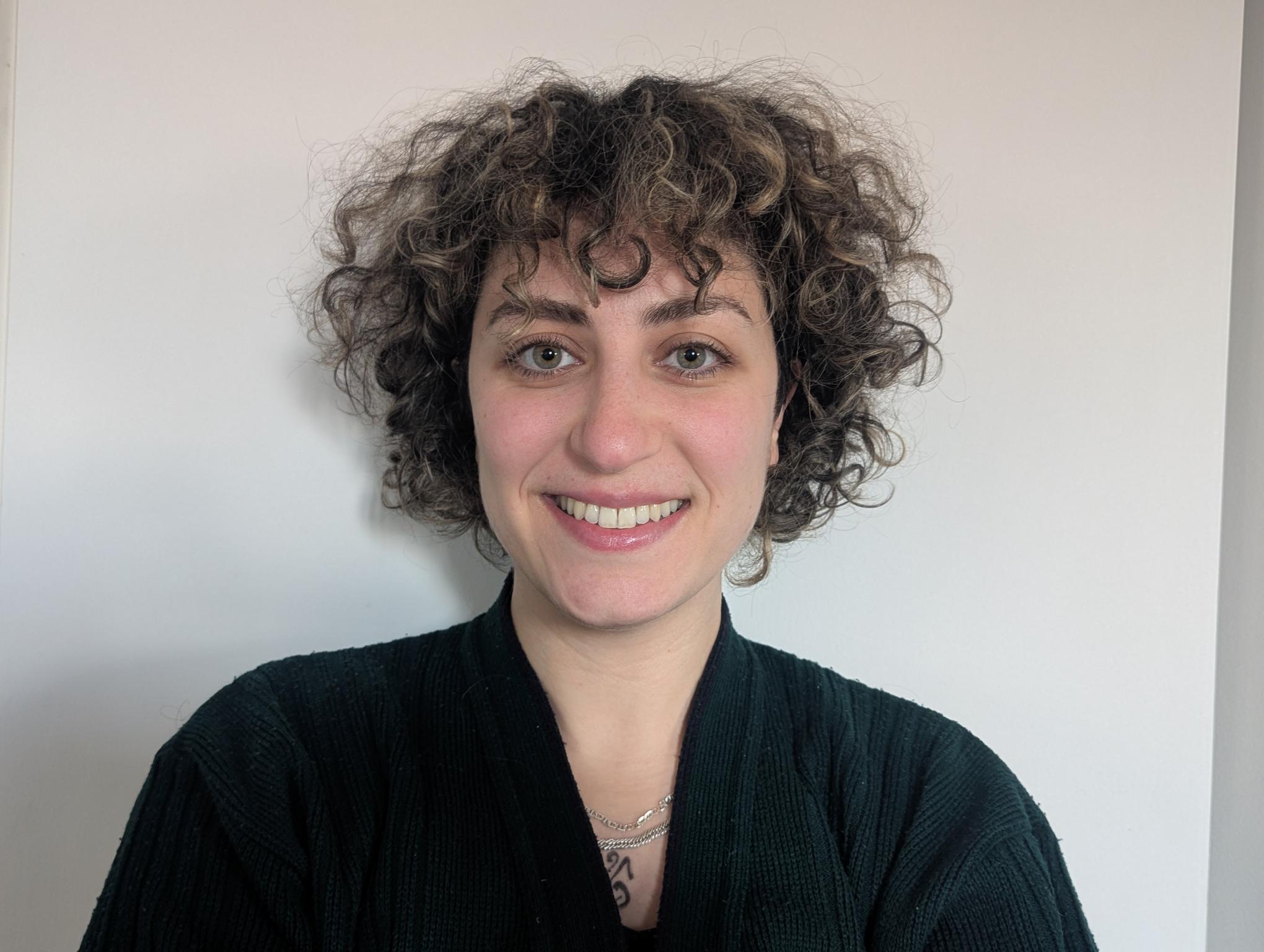 A woman dress in black smiles happily at the camera 