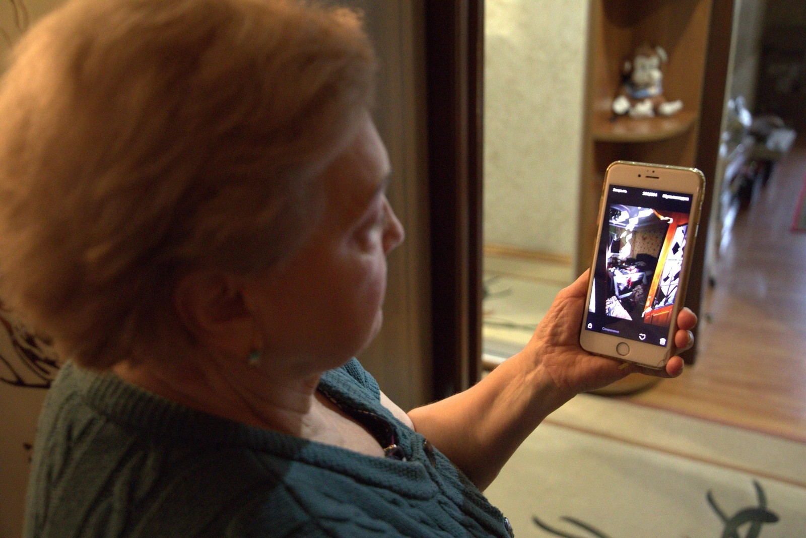 An elderly woman looks at her phone, viewing photos that appear unclear