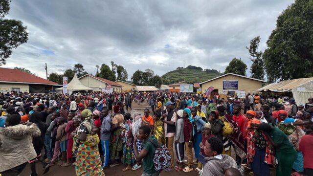 Large crowds of people stand at an overcrowded reception centre.