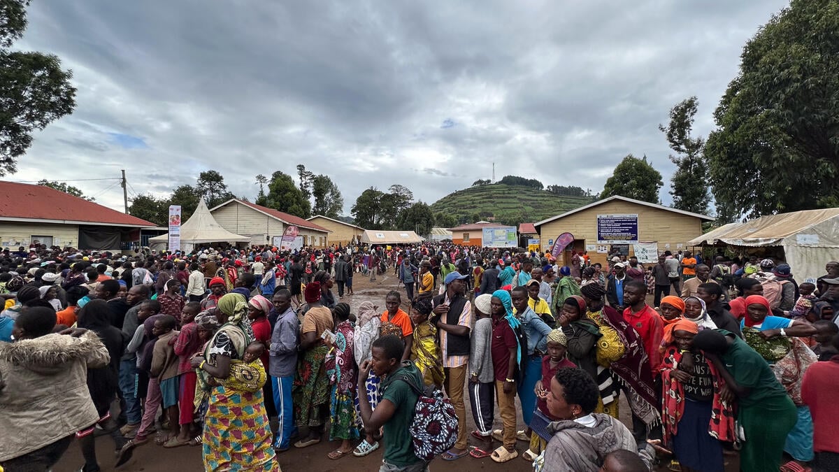 Large crowds of people stand at an overcrowded reception centre.