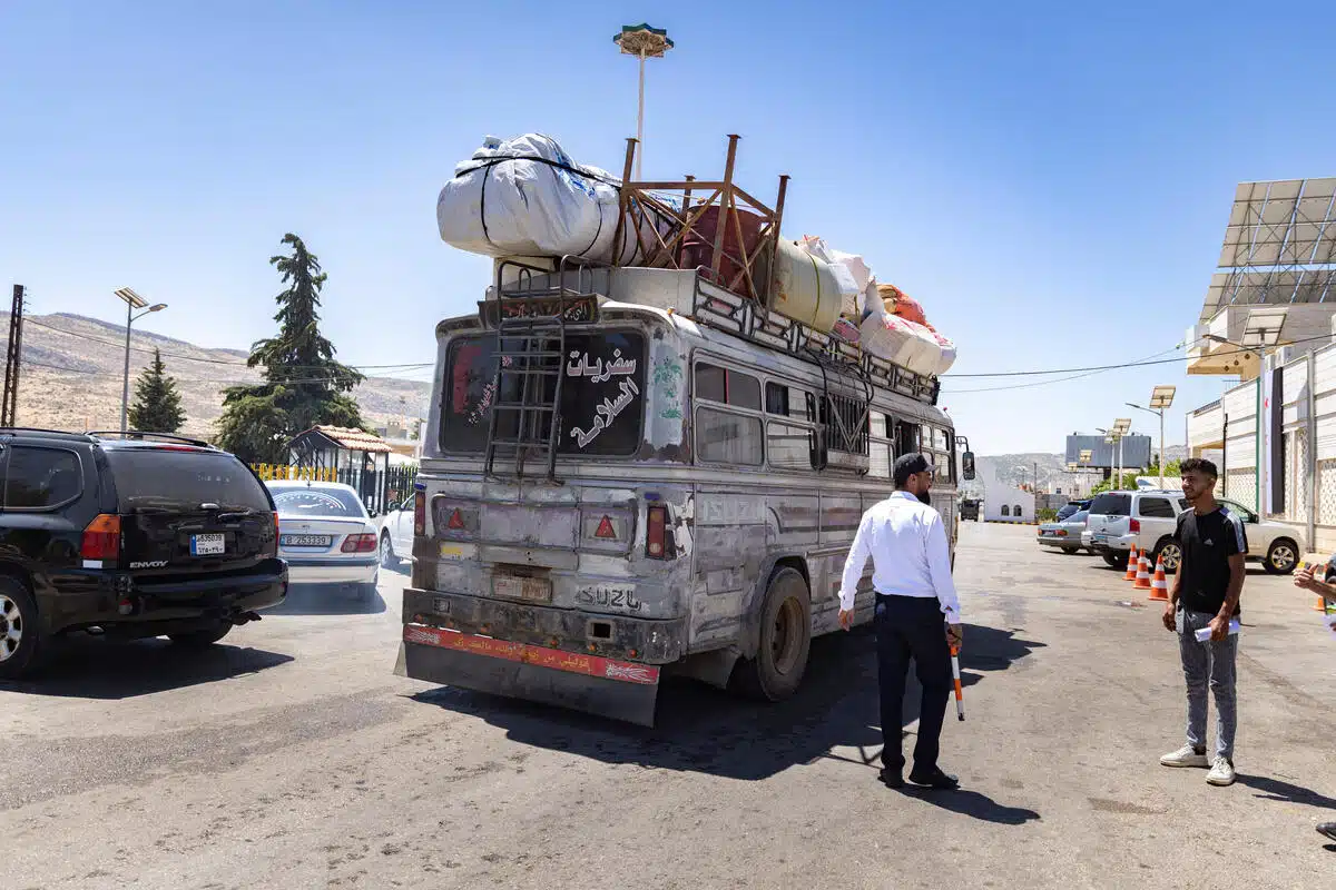 A bus carrying Syrian refugees returning to Syria. A man is standing next to the bus with his back to the camera.