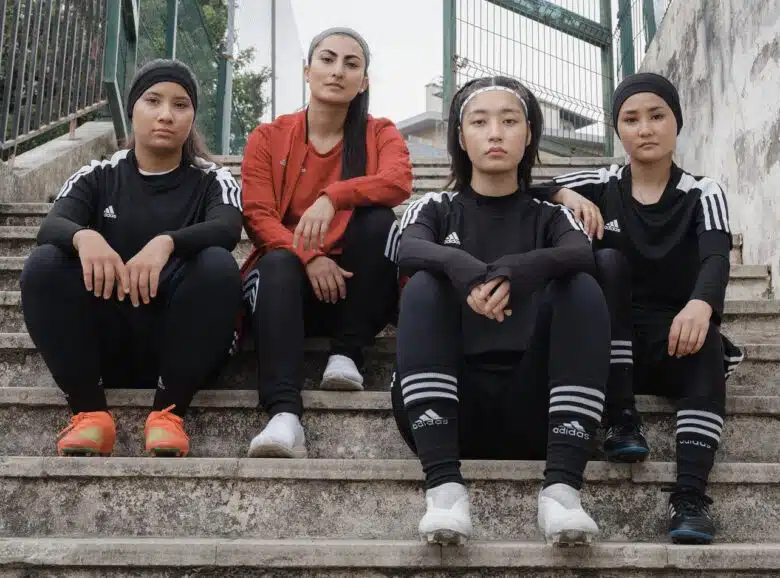 Farkhunda Muhtaj sits on outdoor stairs with three members of the Afghan Women’s National Team.