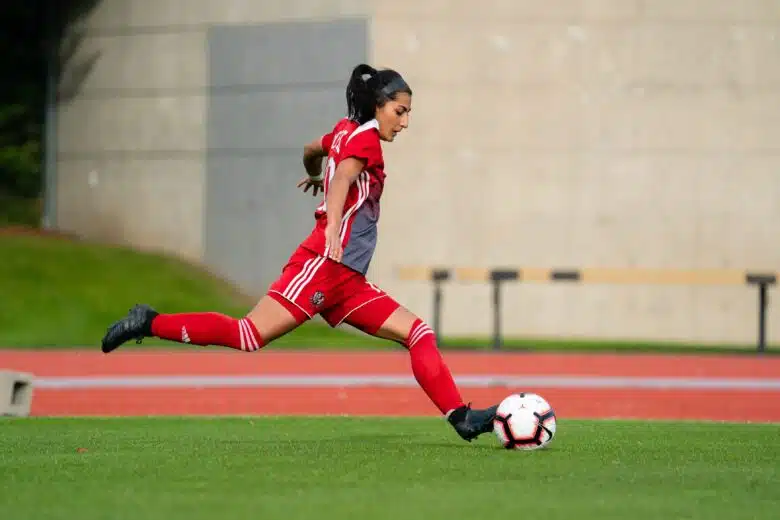 Farkhunda Muhtaj, wearing a red soccer uniform, runs across a green soccer field.