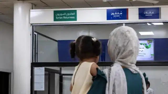 A woman with a white hijab holding a toddler with her hair tied into two braids