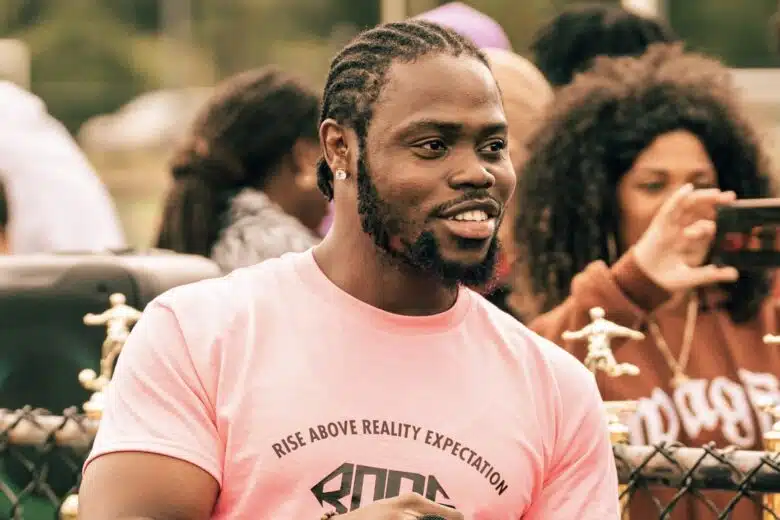 Dacious Richardson smiles, wearing a pink shirt that reads 'rise above reality expectation'