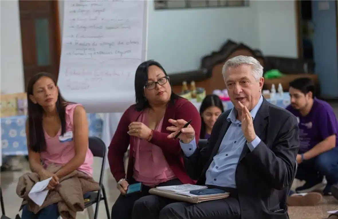 UN High Commissioner for Refugees Filippo Grandi, in a dark blue suit and light blue shirt, gestures as he speaks to an attentive audience.