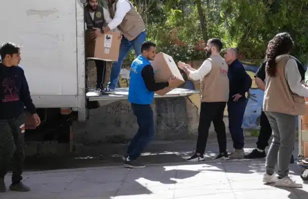 UNHCR staff are seen unloading cardboard boxes from the back of a truck.