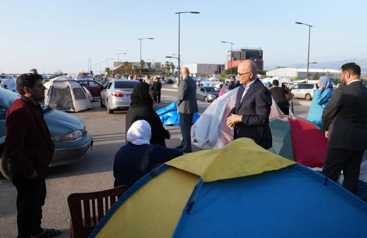 UN High Commissioner for Refugees Barham Salih (centre) speaks to internally displaced Lebanese families at a parking lot filled with pitched camping tents and parked cars in Beirut.