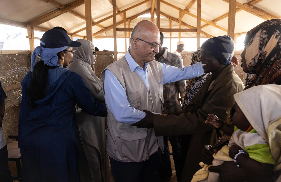 UN High Commissioner for Refugees Barham Salih is seen shaking hands and speaking with a smiling Sudanese refugee and his family at in a crowded reception centre at the Adre border crossing in Chad.