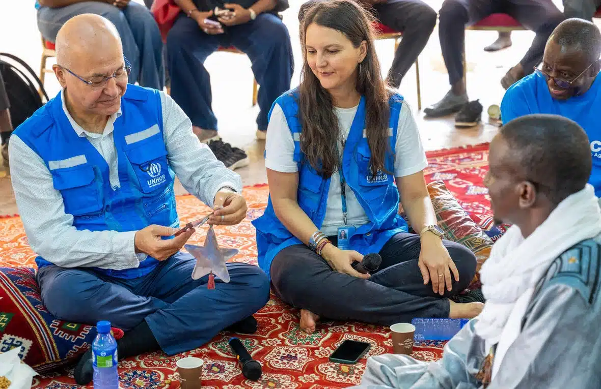 UN High Commissioner for Refugees Barham Salih sits cross-legged on a carpet as he interacts with refugees and UNHCR staff.