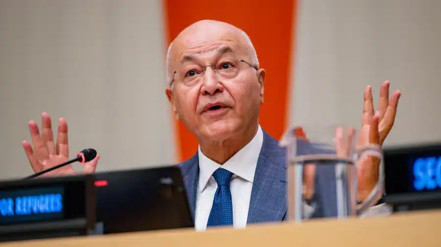 UN High Commissioner for Refugees Barham Salih raises his his hands sitting behind a podium as he welcomes States and partner organizations to a high-level event commemorating the 75th anniversary of the 1951 Refugee Convention at UN headquarters in New York.
