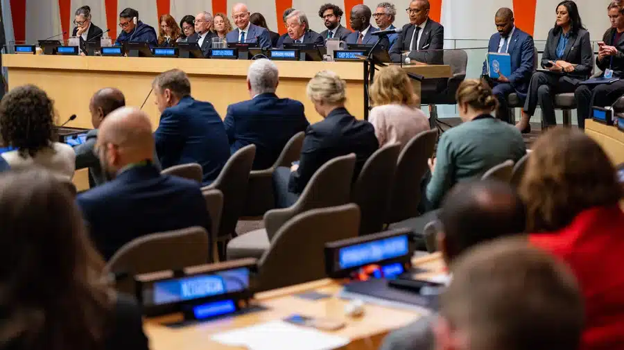 People are seen sitting behind desks with country names and microphones in a large circular-shaped room at the UN headquarters in New York.